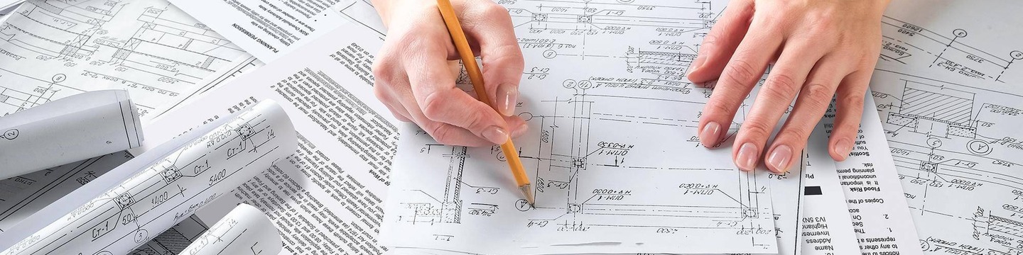 Hand holding pencil examining plans