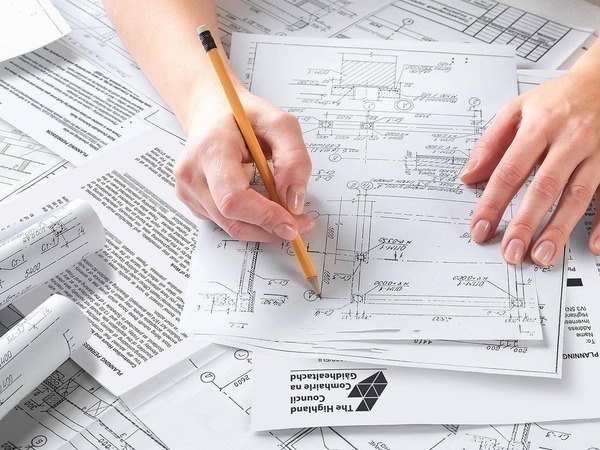 Hand holding pencil examining plans