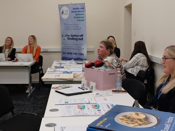 People at an information event with leaflets on tables 